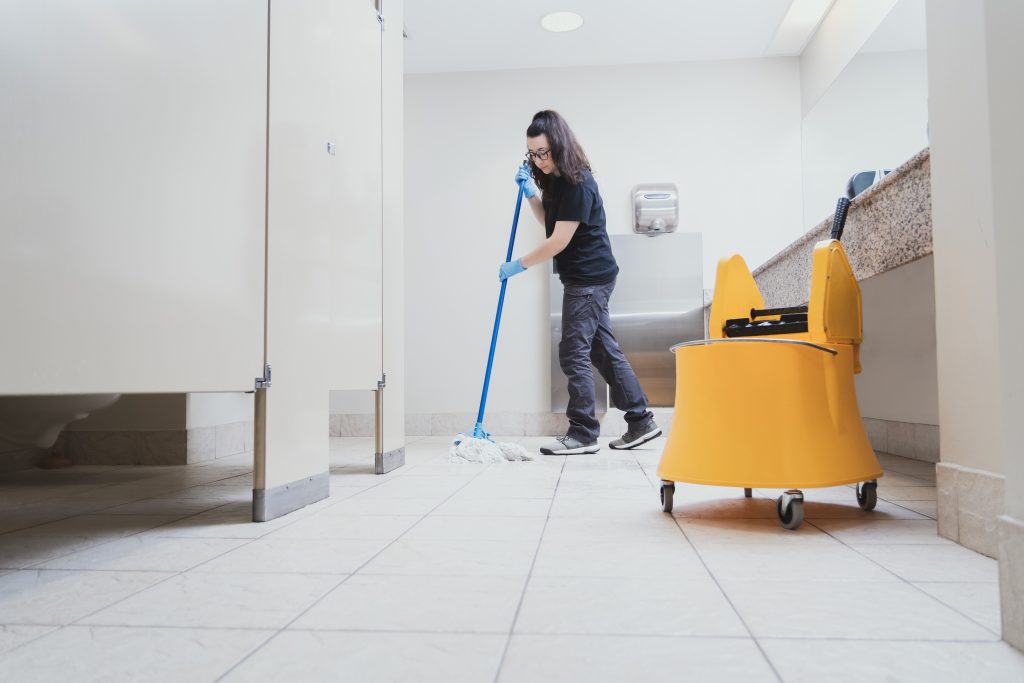 cleaning lady mopping a bathroom using a yellow bucket