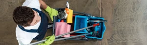 A man carrying a bucket with cleaning supplies and tools
